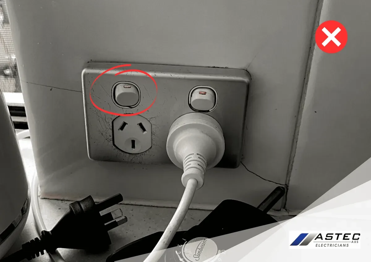 Cracked power outlet with a plug inserted, circled as a hazard