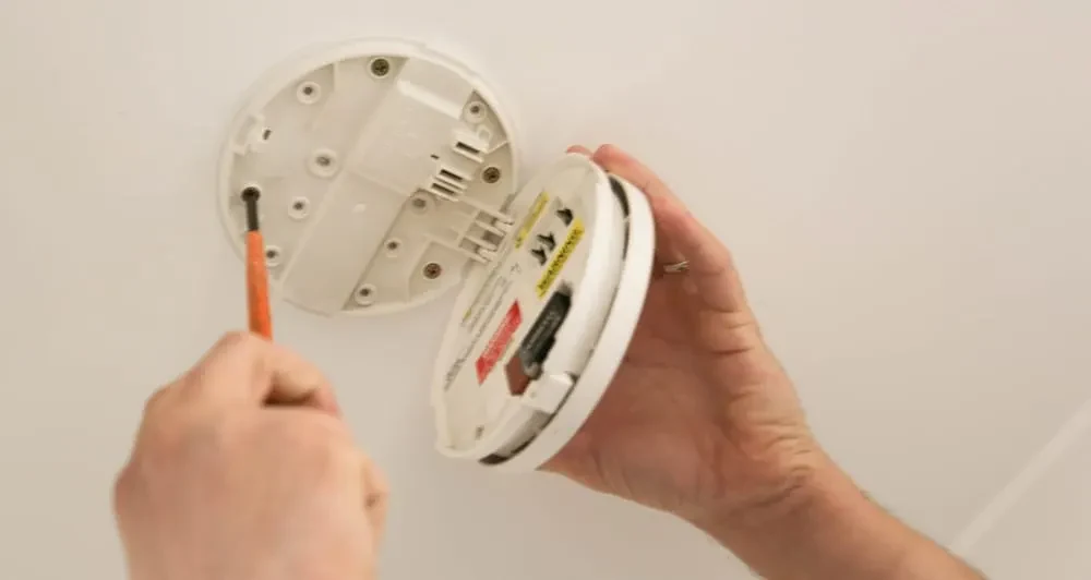 Electrician servicing a smoke alarm
