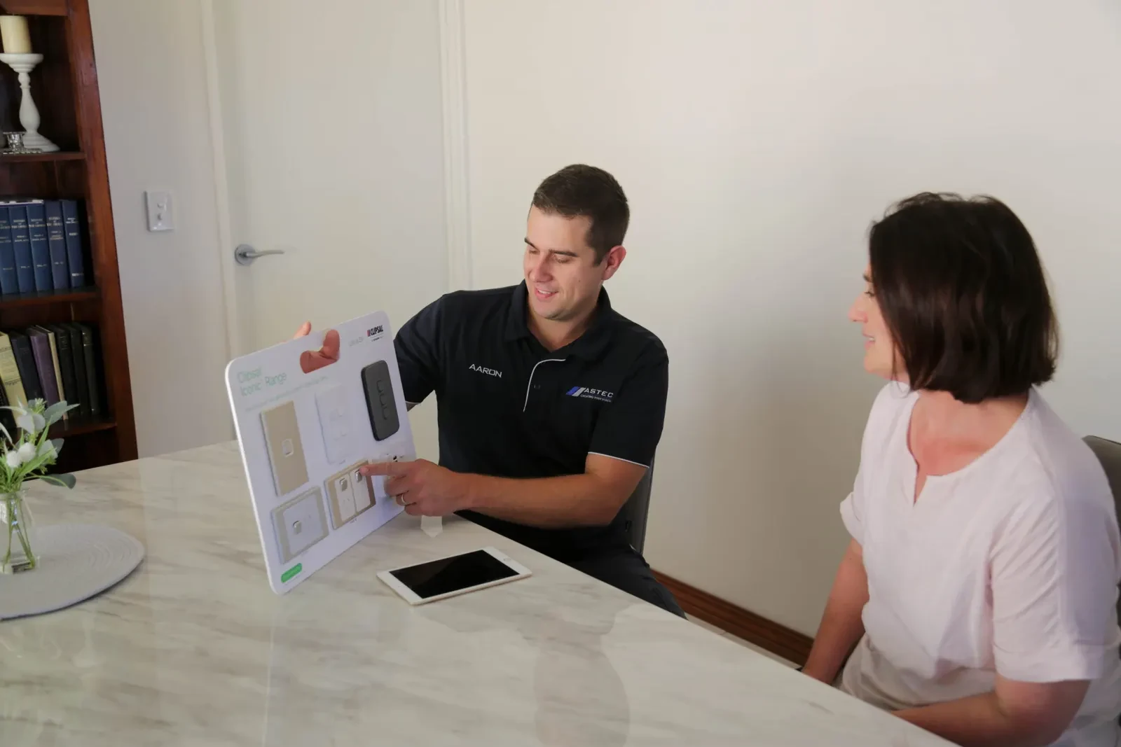 ASTEC electrician walking a homeowner through switch and fitting options at her kitchen bench